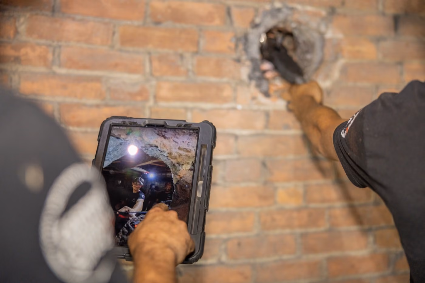 Chimney technician holding a tablet that is displaying a live internal chimney inspection feed from a camera