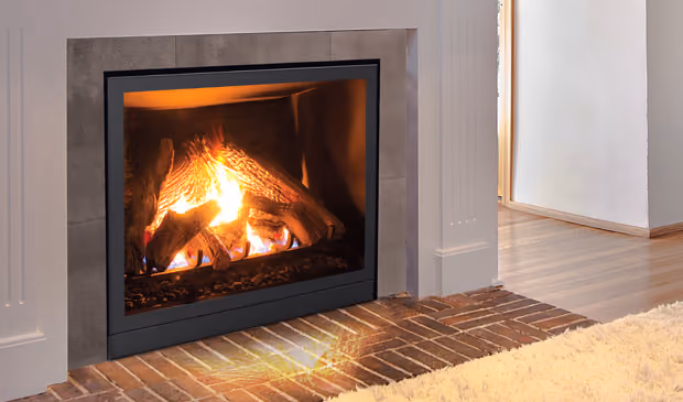 Modern gas fireplace with flames and logs set in a tiled hearth with wood floor and rug nearby.