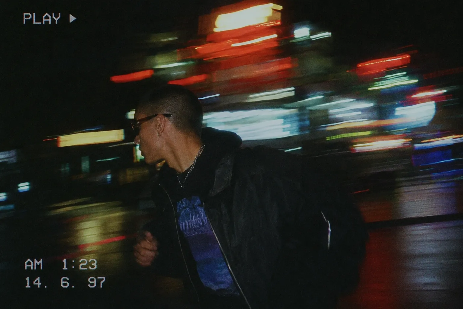 Motion-blurred night shot of a young man running past streaking city lights,  late-90s look