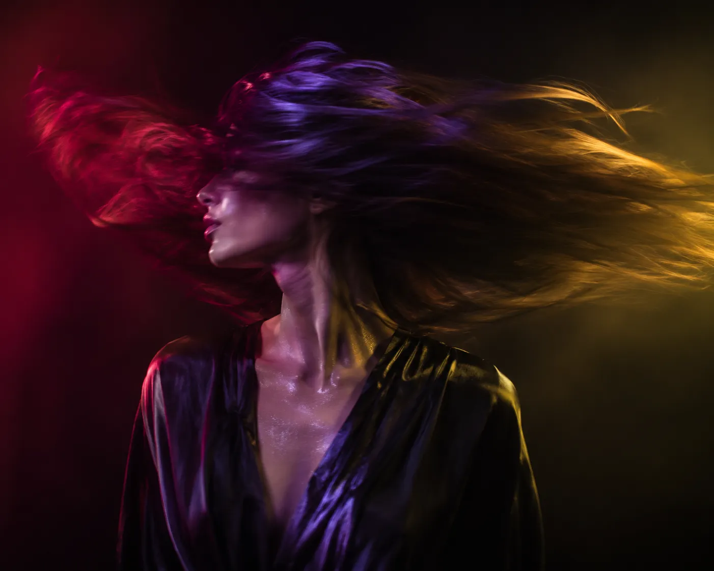 Woman with long hair sweeping through violet, crimson, and amber light