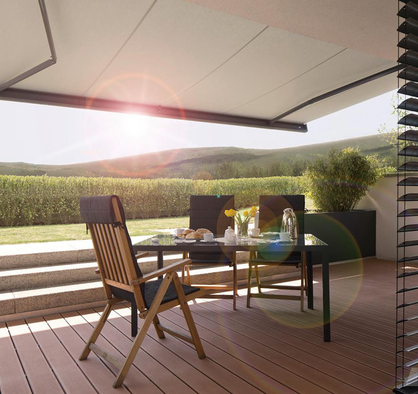 Markise über einer Terrasse mit Holzstühlen