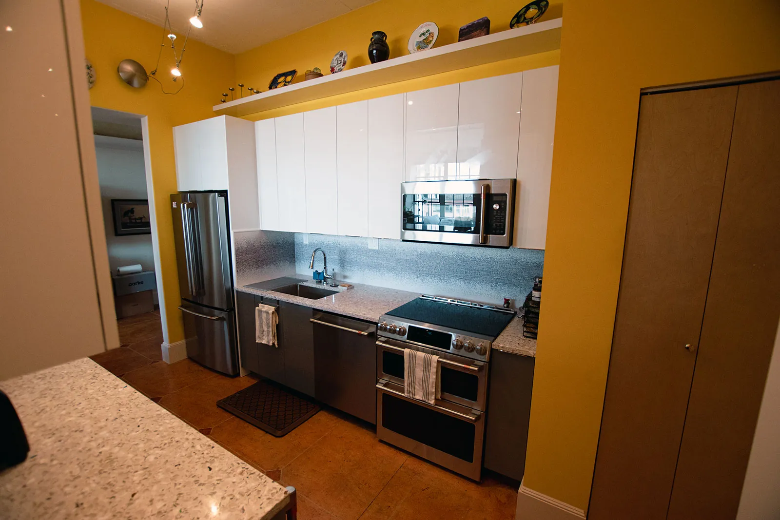 Pearl District kitchen with glossy white upper cabinets, stainless appliances, and mosaic backsplash