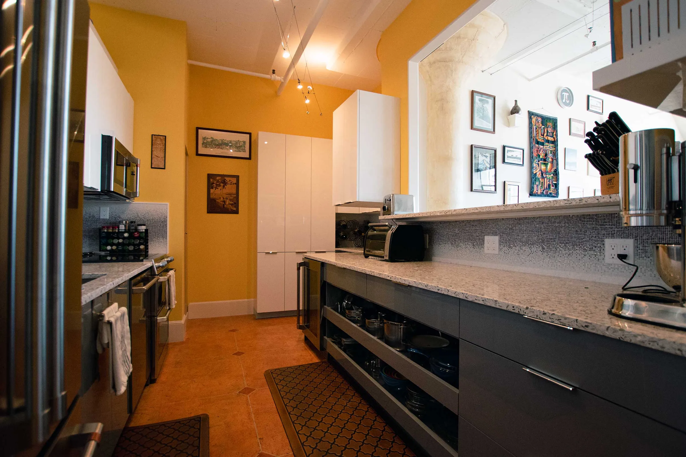 Pearl District galley kitchen with dark lower cabinets, open pull-out shelves, and speckled countertops