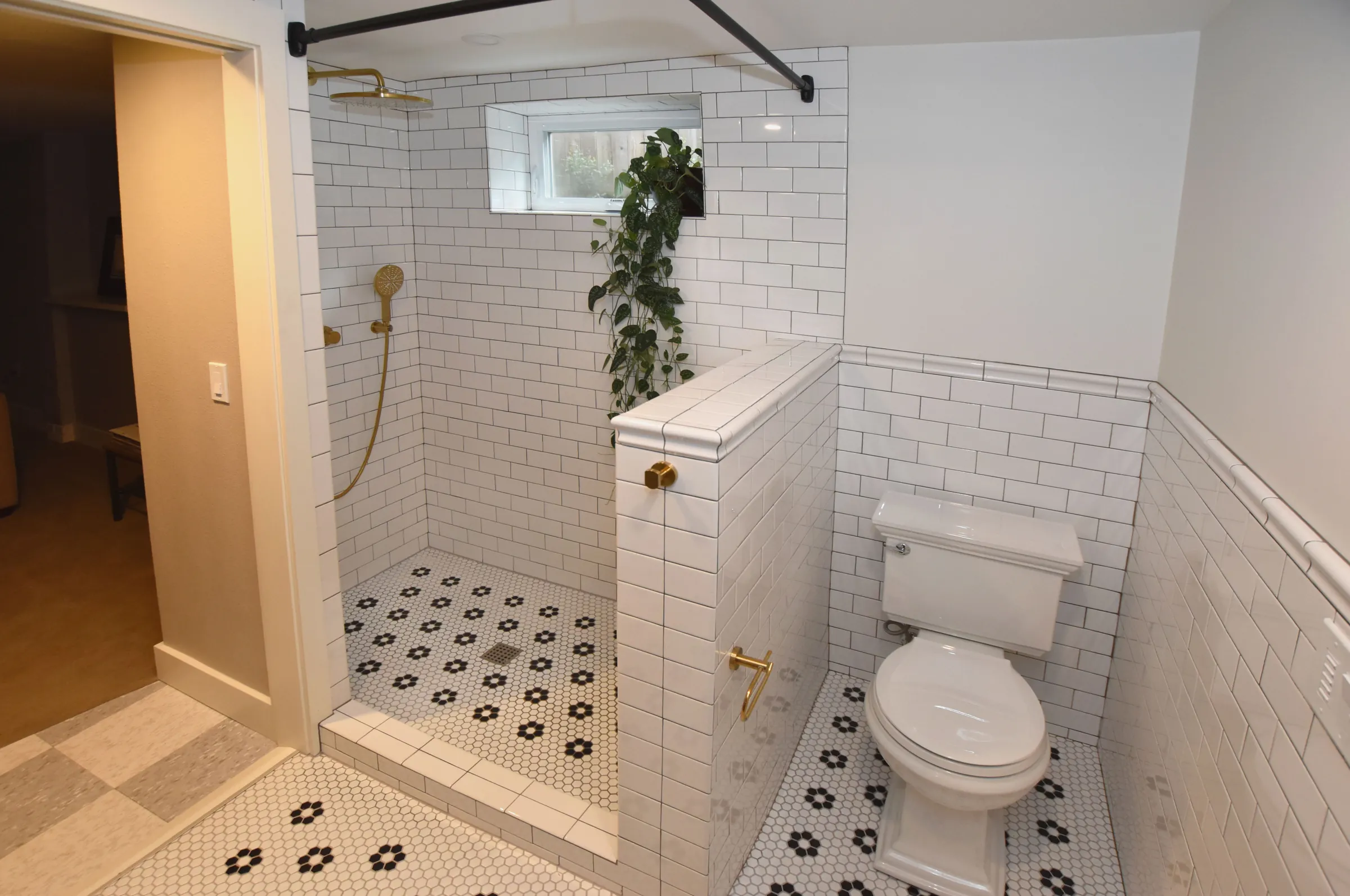 Foster-Powell bathroom with open subway tile shower, tiled half wall, brass fixtures, and hex floor