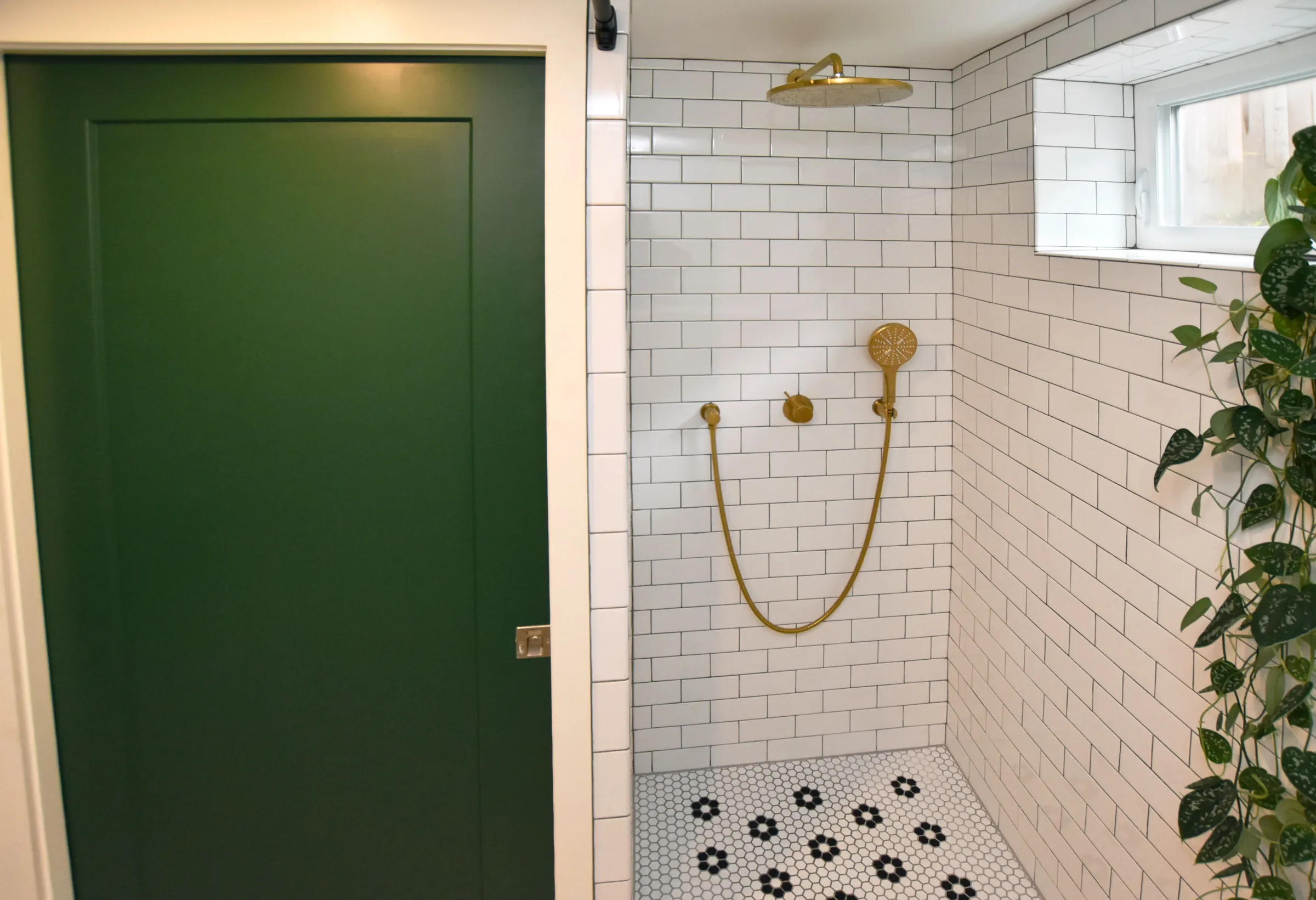 Foster-Powell shower with white subway tile, brass rain and handheld showerheads, and green door