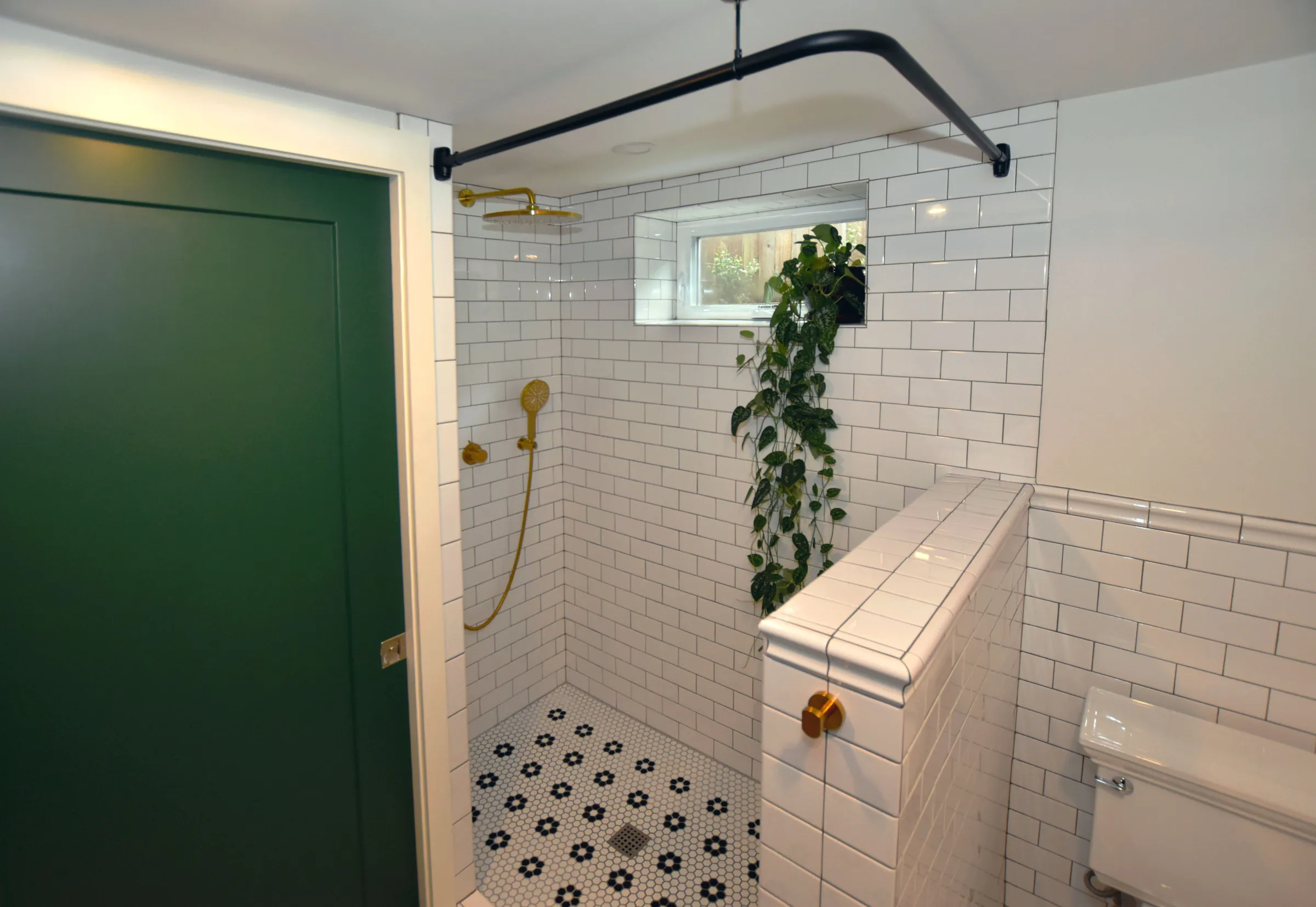 Foster-Powell bathroom with green door, subway tile shower, and brass fixtures