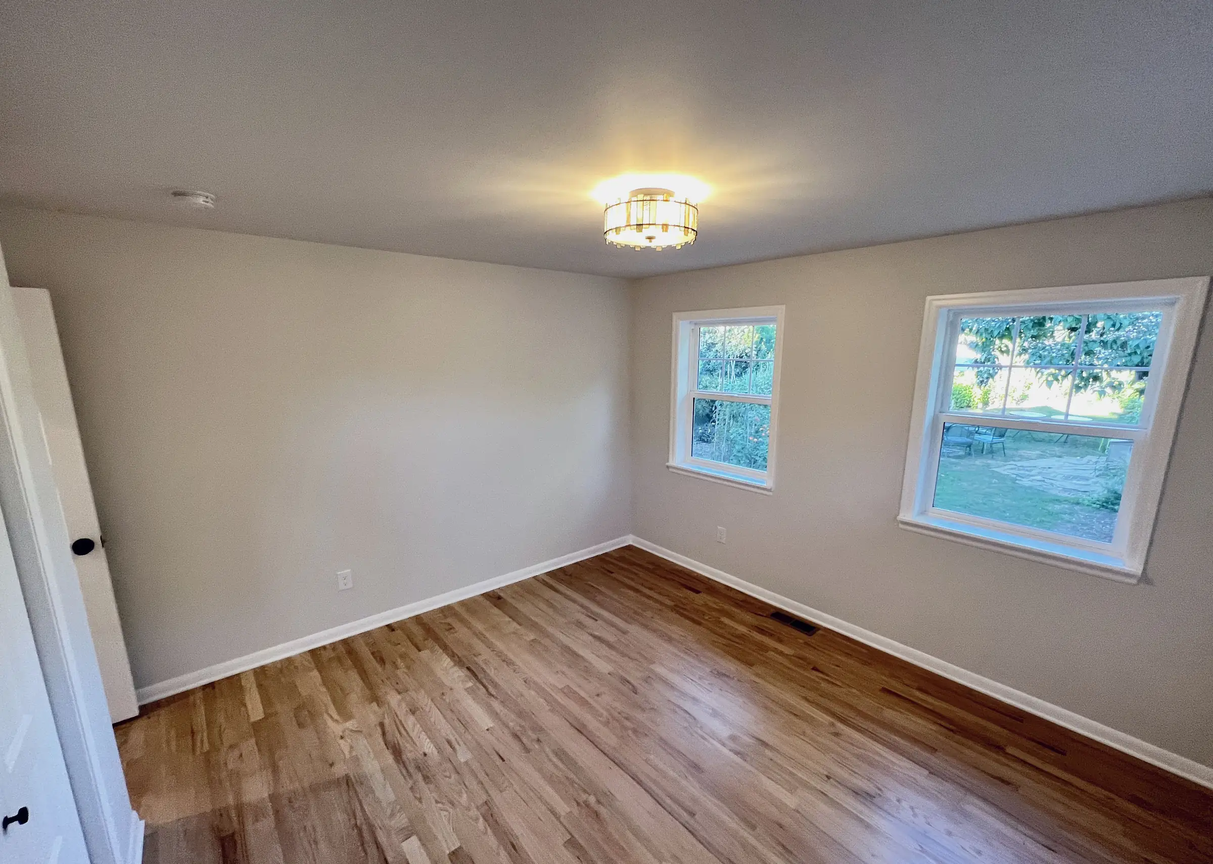 Milwaukie addition bedroom with hardwood floors, ceiling light, and two windows