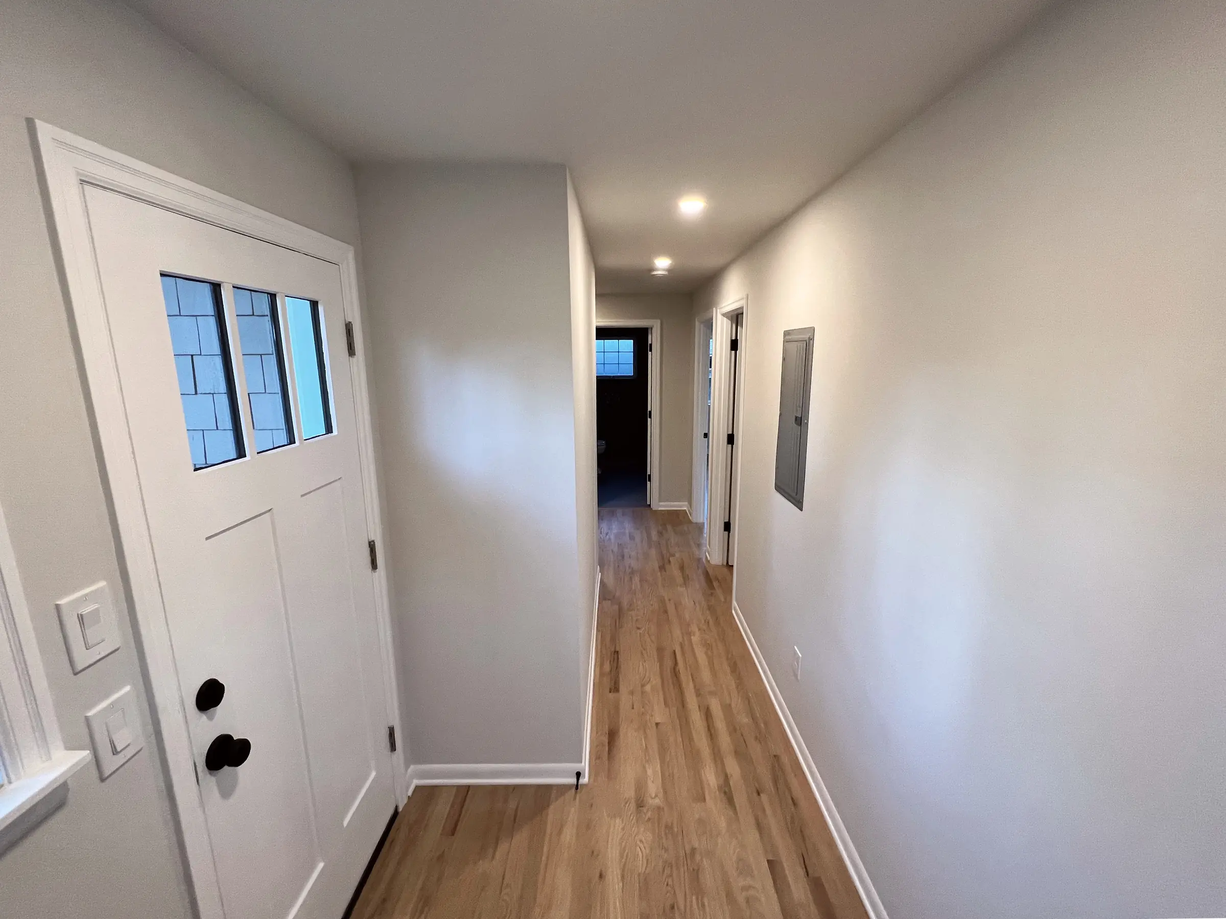 Milwaukie addition hallway with hardwood floors and craftsman-style exterior door