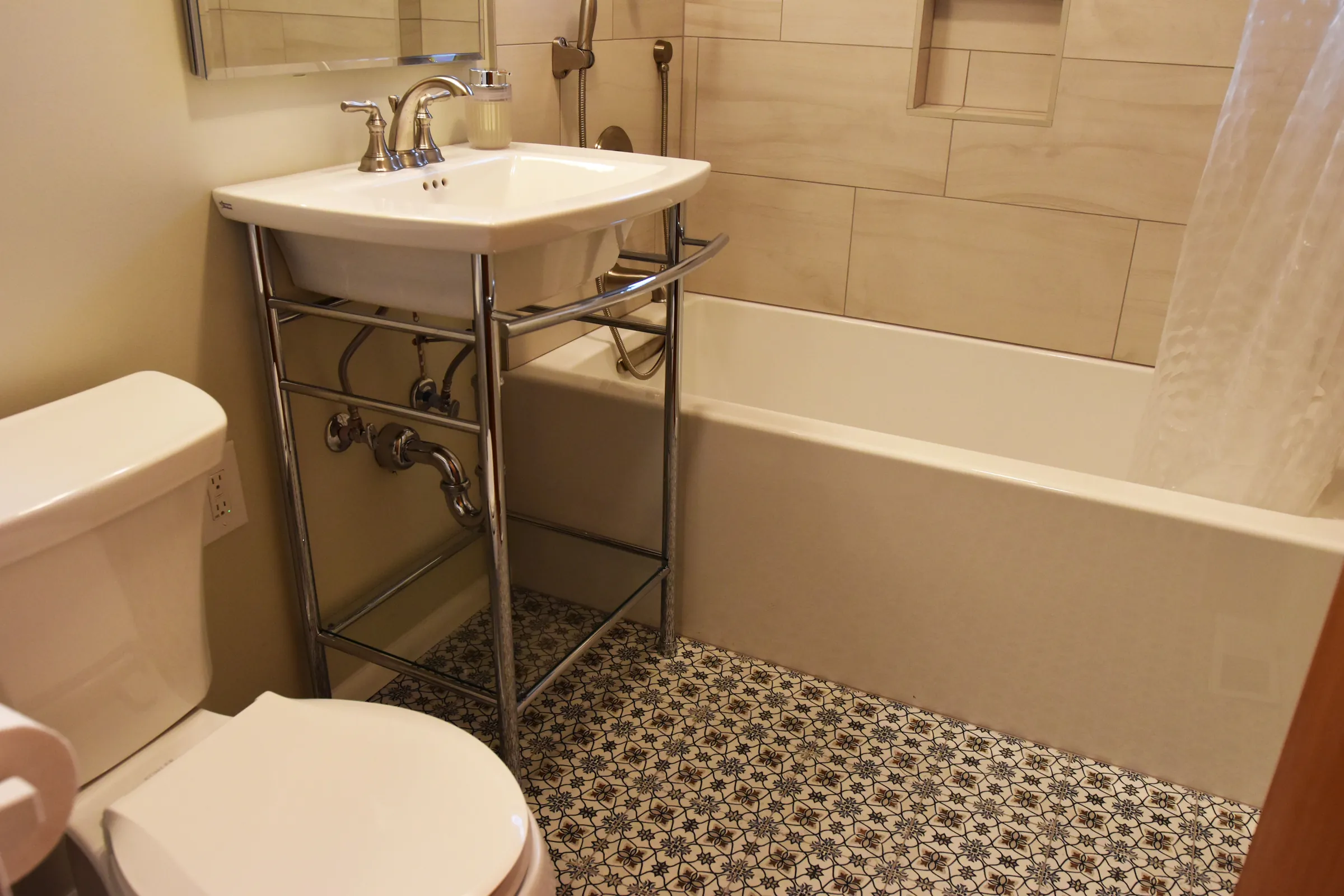 Gateway bathroom console sink with chrome legs beside the tub and patterned floor tile