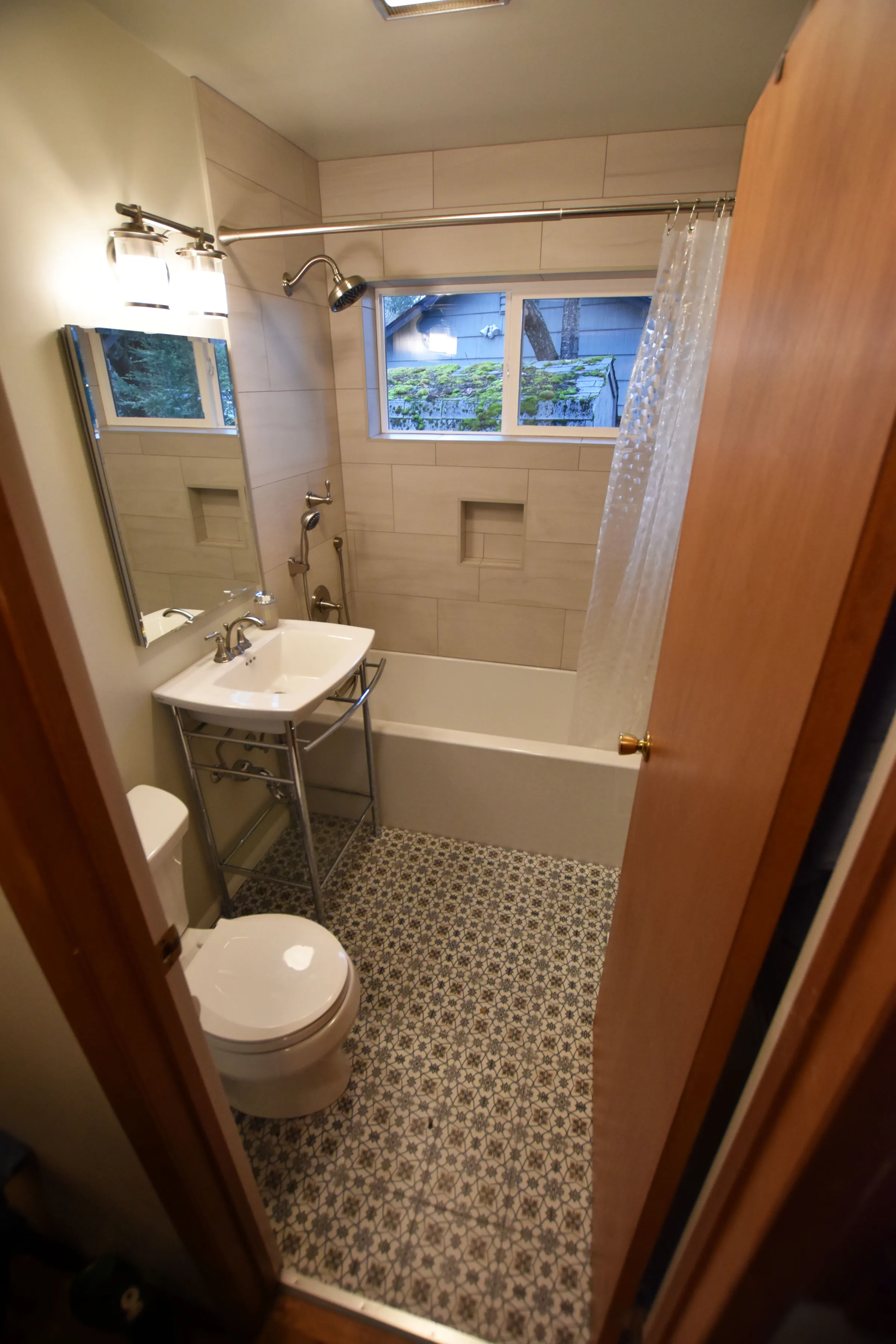 Gateway bathroom from the doorway showing tub, console sink, window, and patterned tile floor