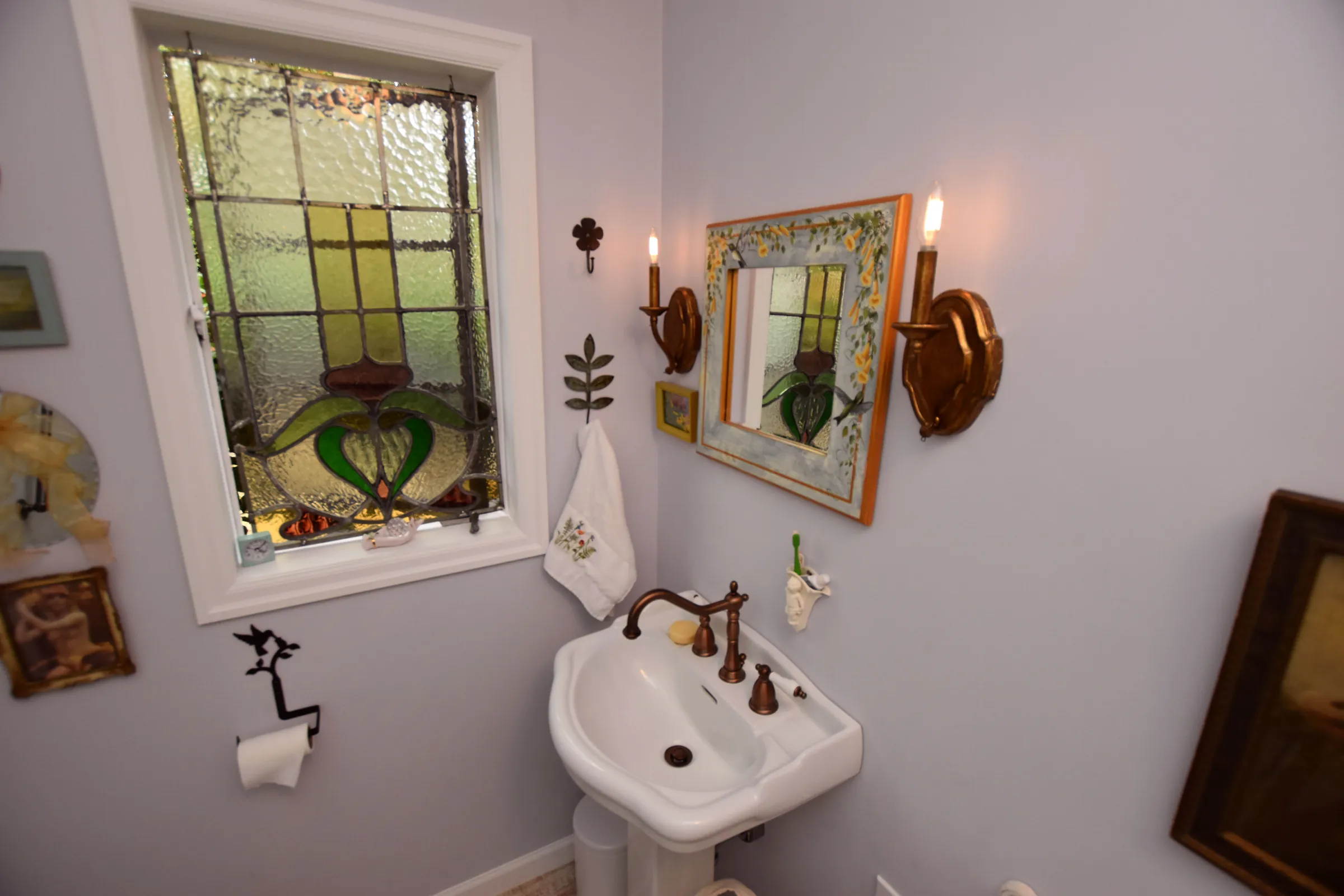 Gladstone bathroom with stained glass window, pedestal sink, bronze faucet, and candle sconces
