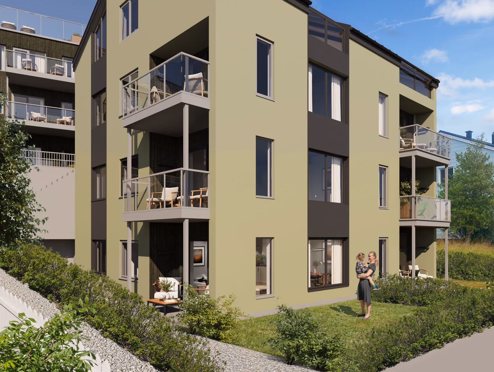 Modern apartment building with balconies, greenery, and a woman holding a child on the lawn.