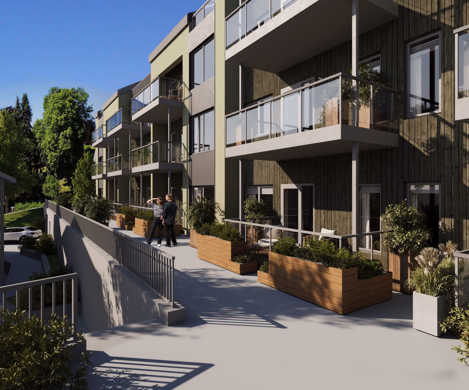 Modern apartment building with balconies, planters, and two people standing on the pathway outside.