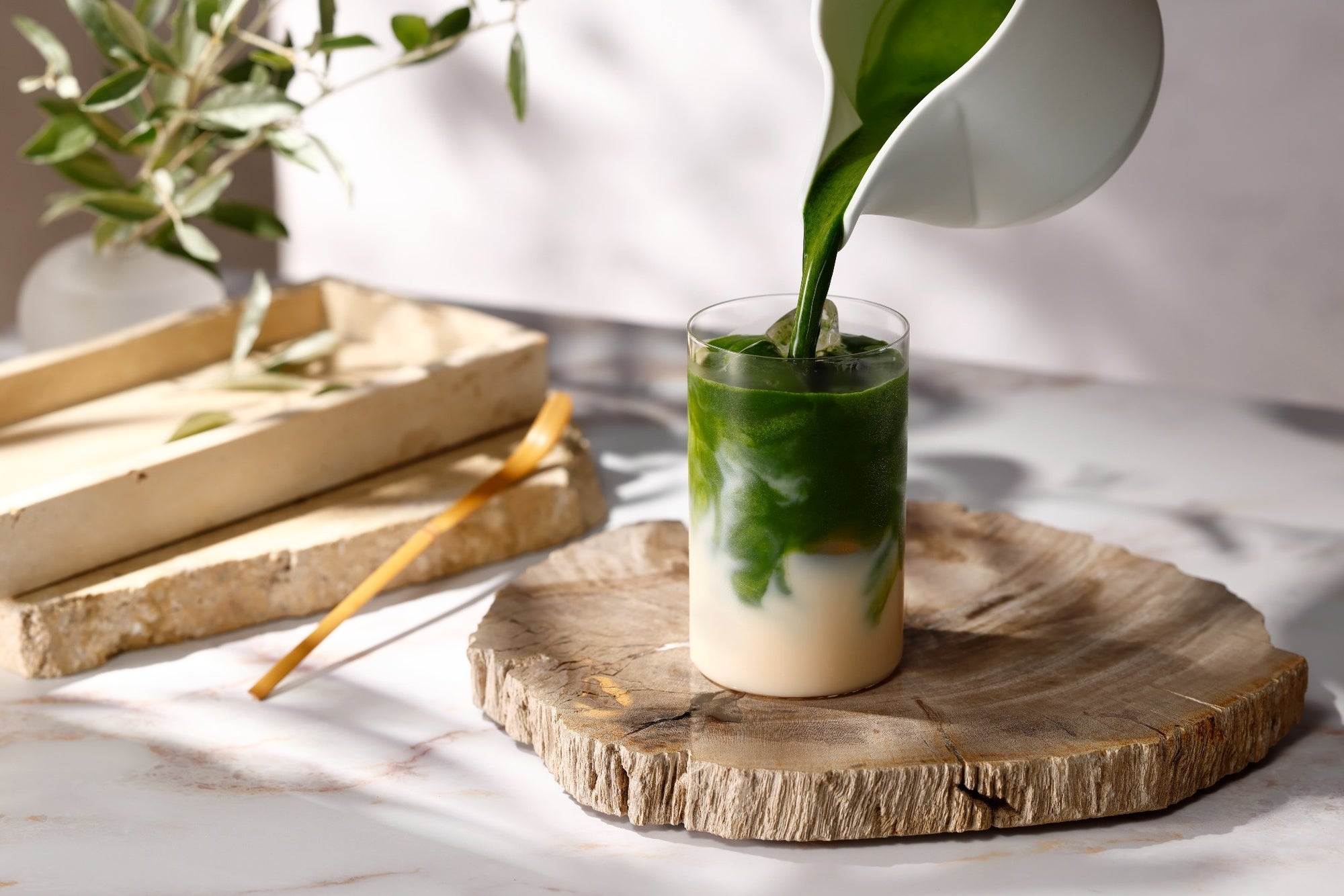 Matcha being poured into a glass of oat milk