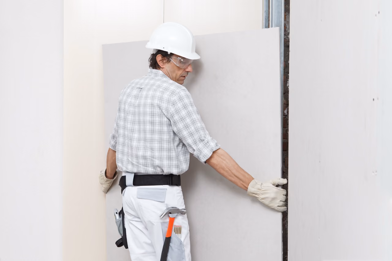 worker carrying plasterboard