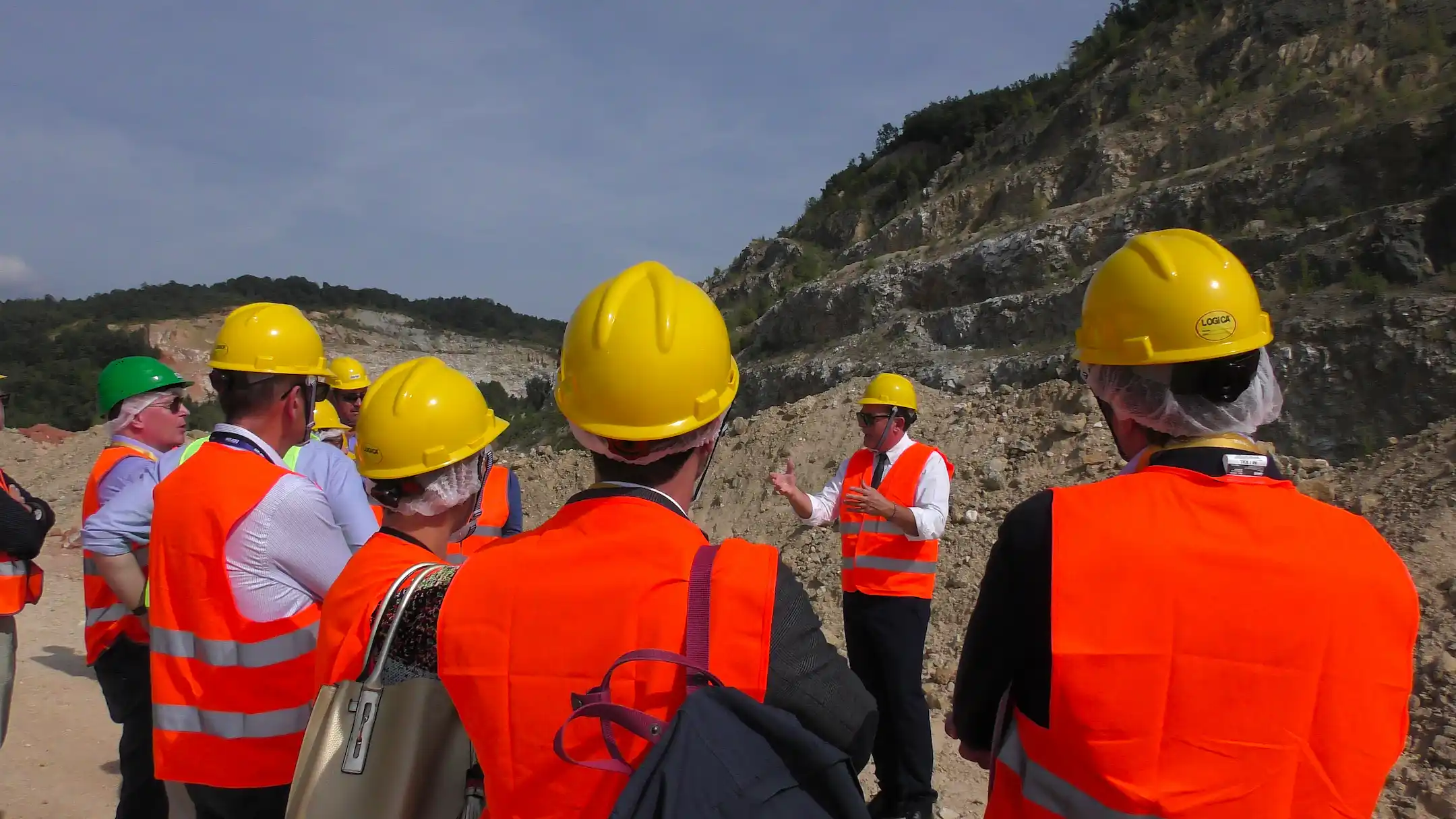 A group of people in a quarry wearing helmets.