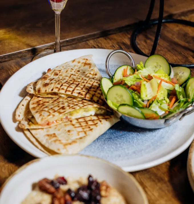 Grilled quesadillas on a plate served with a side salad of cucumber, lettuce, and carrots.