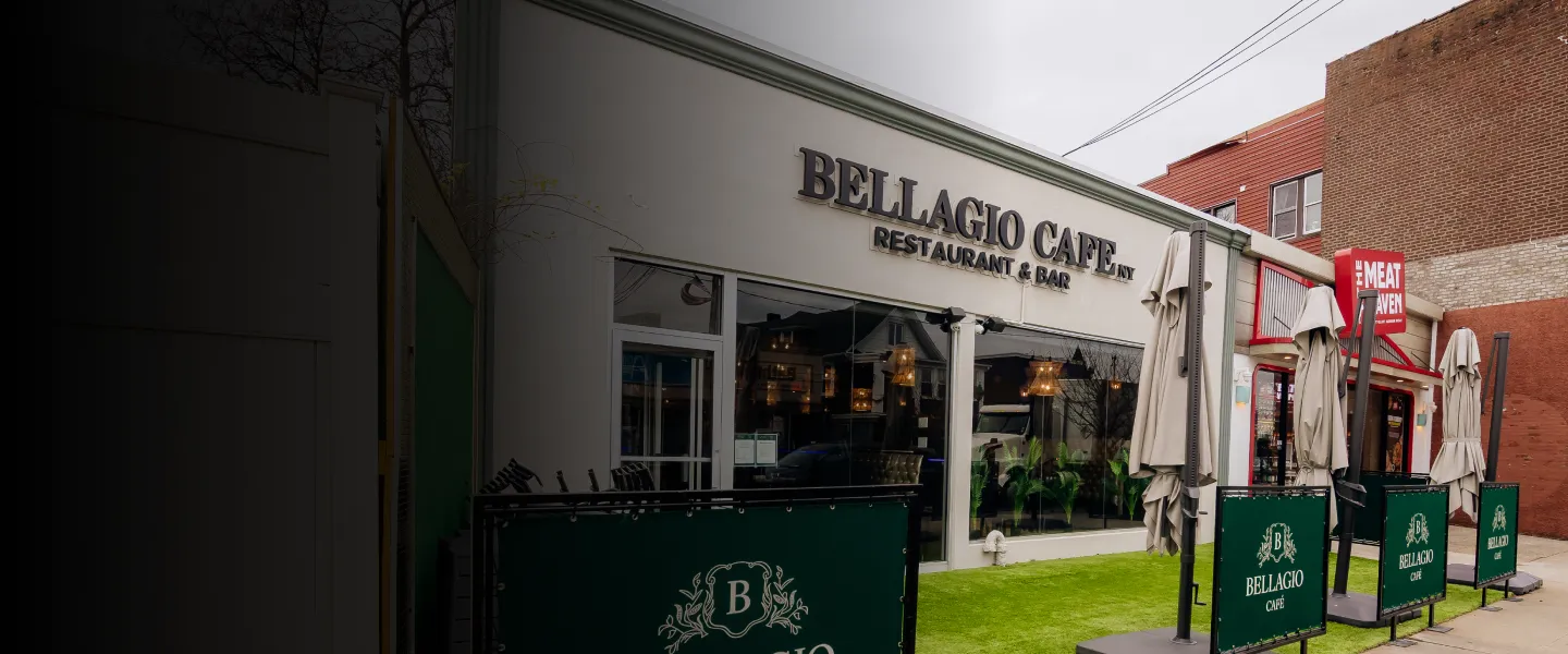 Outdoor seating area of Bellagio Café restaurant and bar with closed umbrellas on a green turf patio.