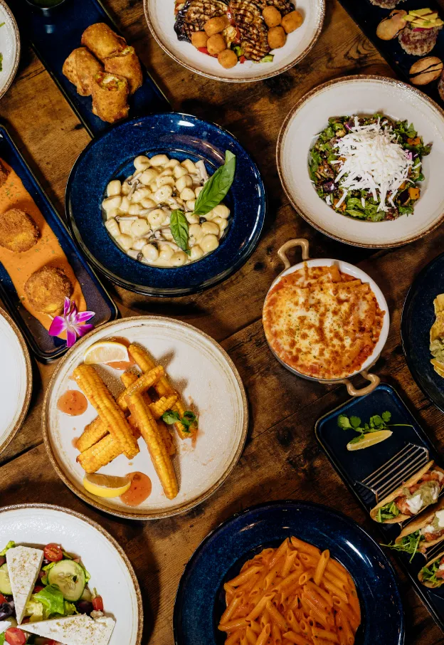 Table with various dishes including pasta, salad, corn, baked dish, and appetizers.