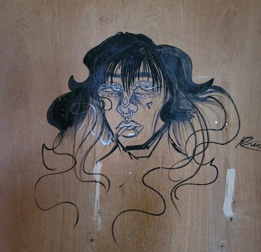 Drawing of a woman with dark hair smoking, with a nose ring and a heart tattoo on her cheek on wood.