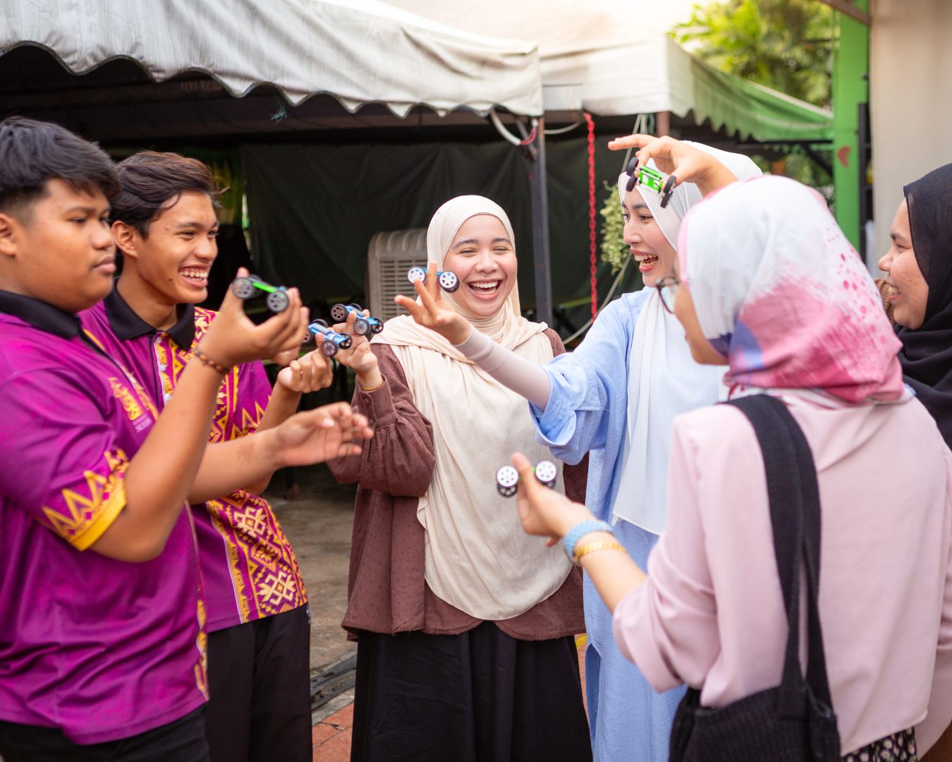 Children and i2 Energy volunteers building toy solar cars together at Rumah Bakti Nur Ain