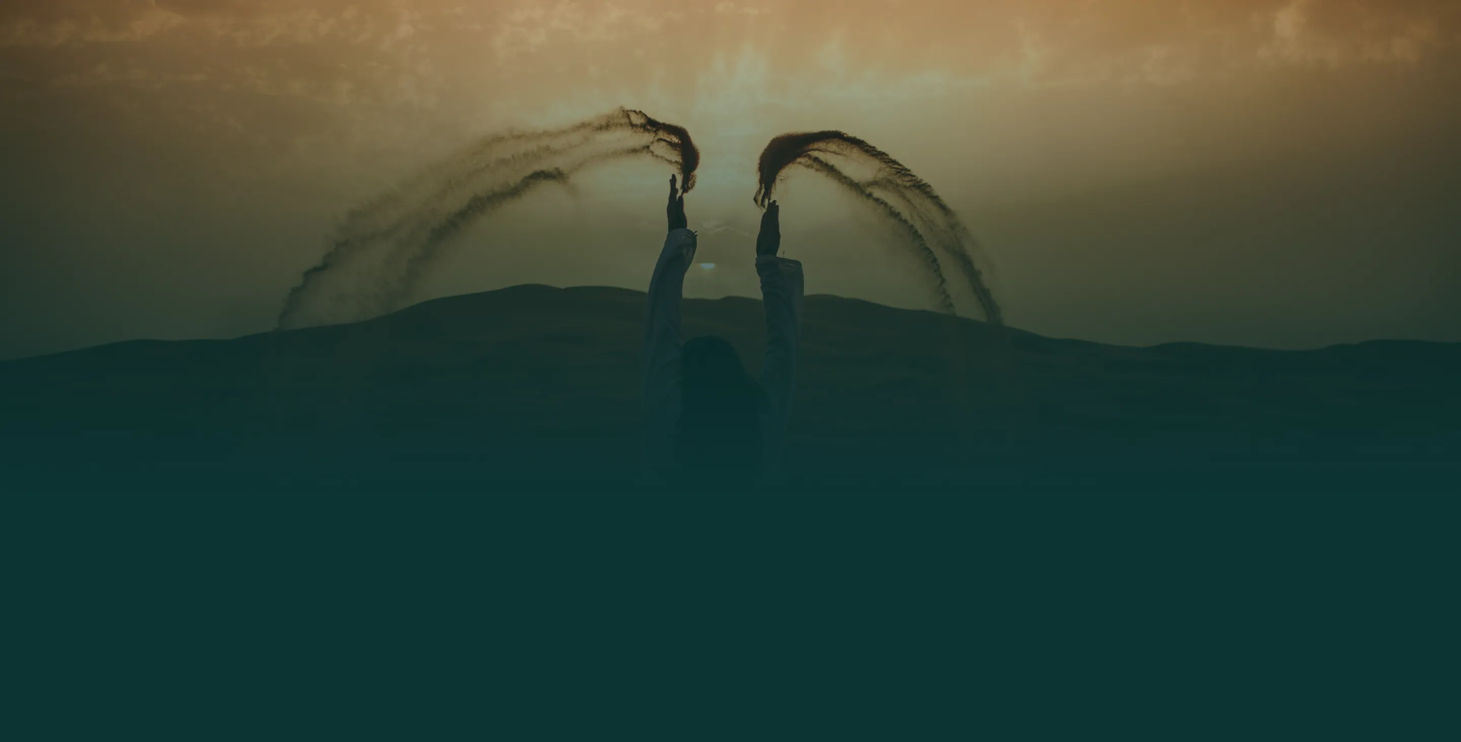 Silhouettes of two people flipping their wet hair against a sunset sky