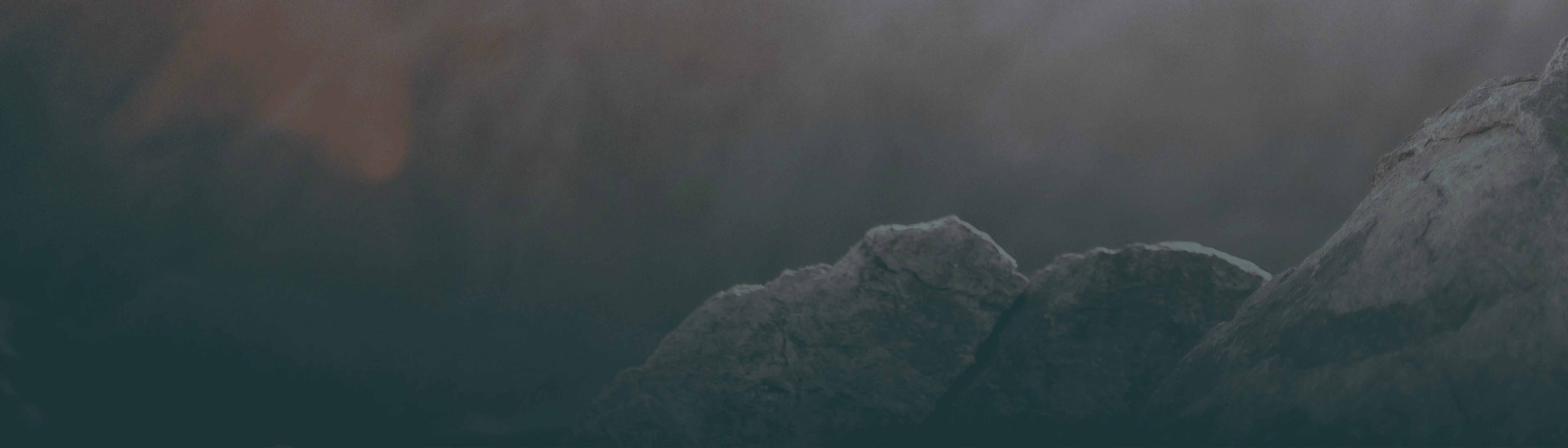 Close-up of large gray rocks under dim, foggy lighting.