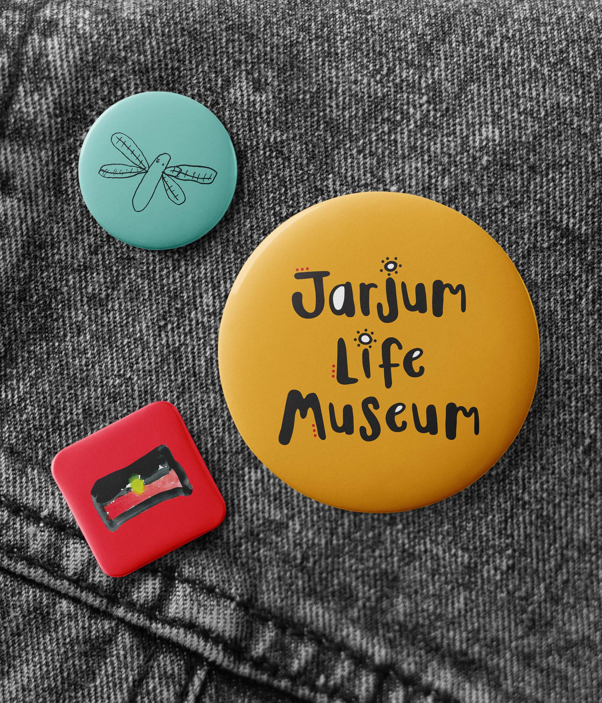 Jarjum Life Museum badges pinned to a denim jacket, featuring the hand-drawn logo and children's artwork