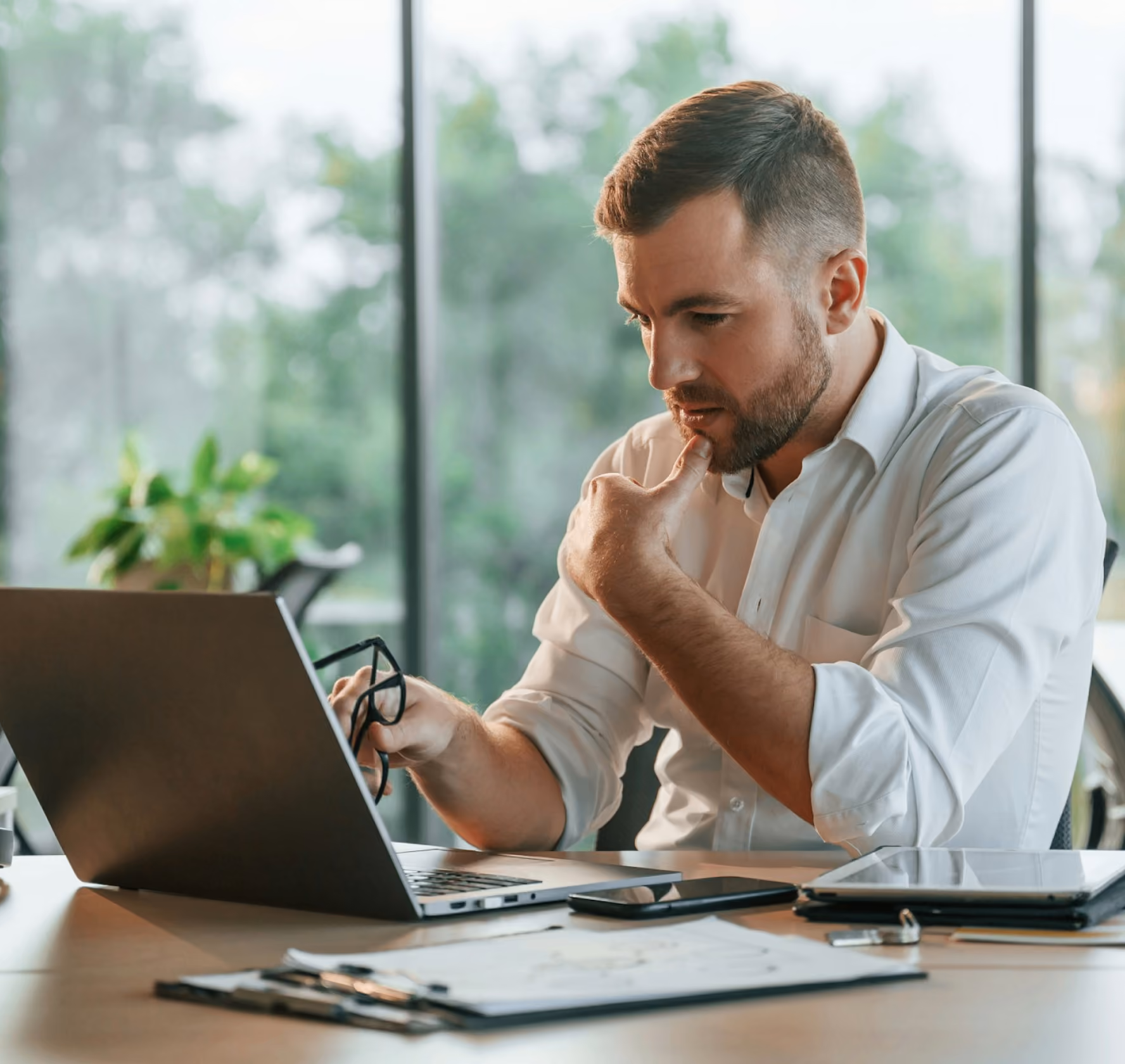 Person working on a laptop at a desk near a window