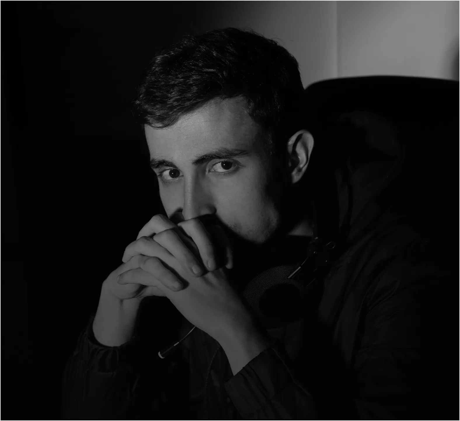 Man with mustache watching a movie in a dark theater with light shining behind him.