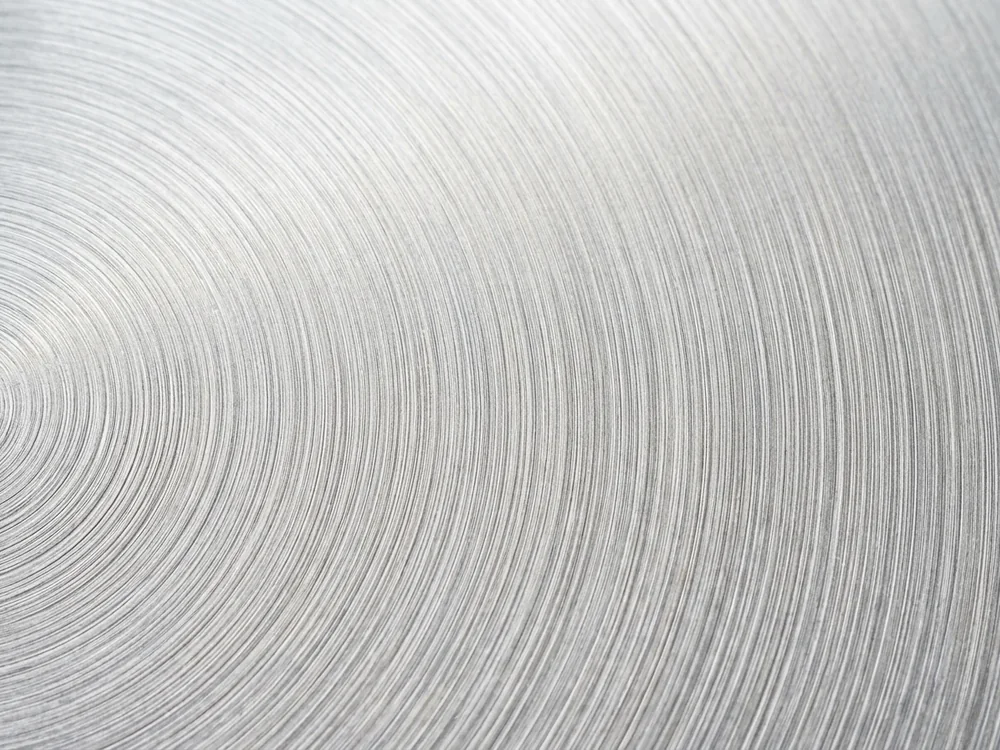 Circular brushed finish on a bright aluminum surface
