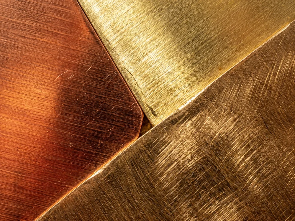 Copper, brass, and bronze sheets overlapping with brushed finishes
