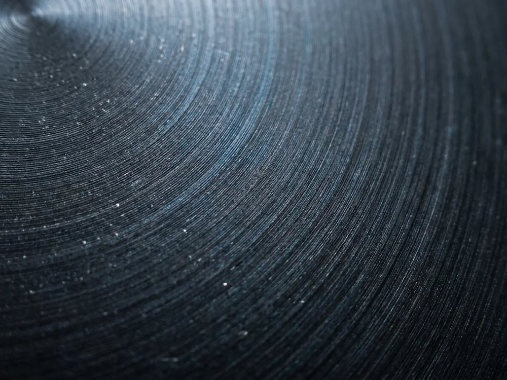 Dark exotic metal surface with fine concentric turning marks