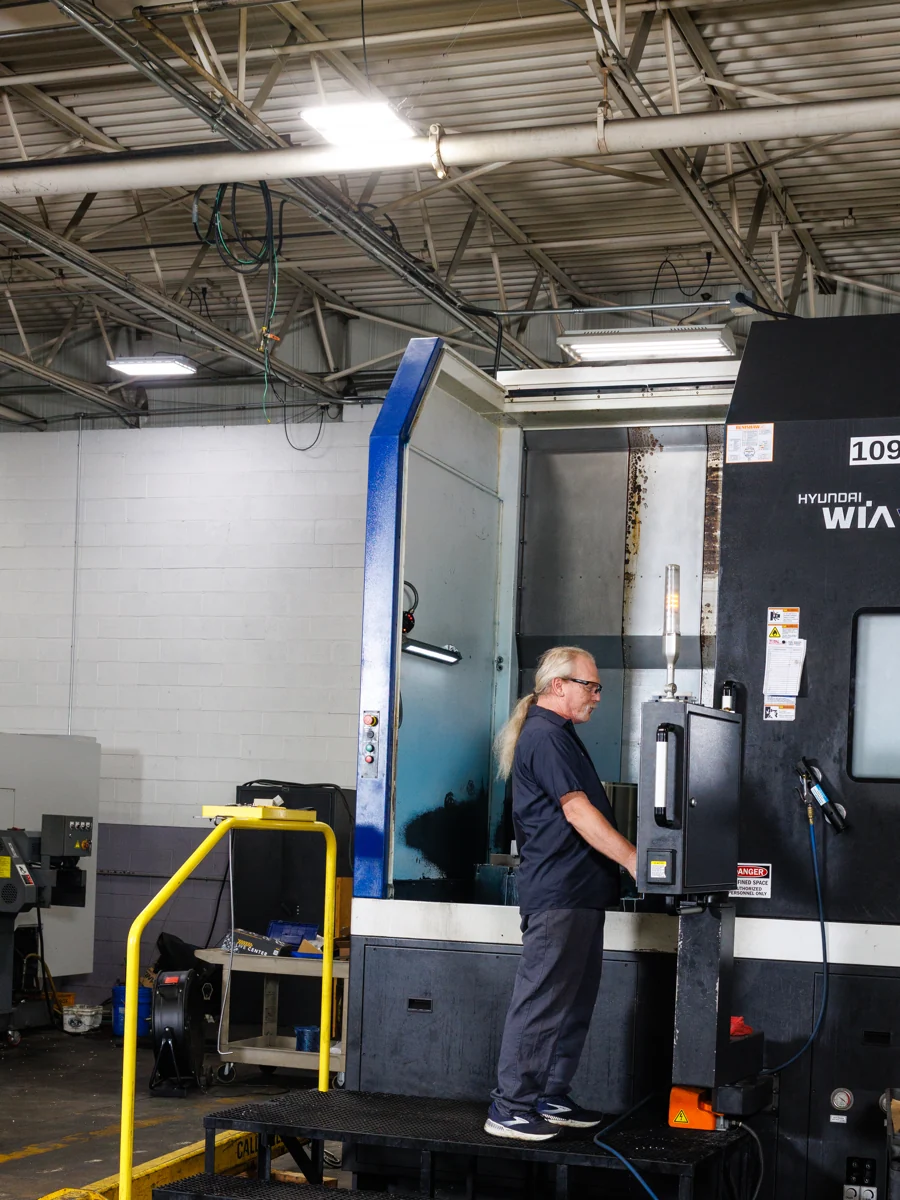 Machinist working at a CNC machining center on the Total Manufacturing floor