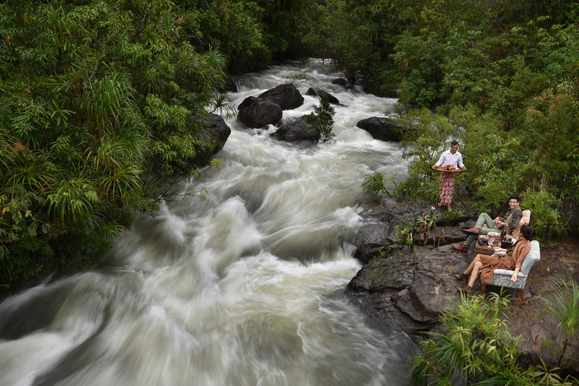 Guests enjoying a private riverside setting with drinks served beside the rapids