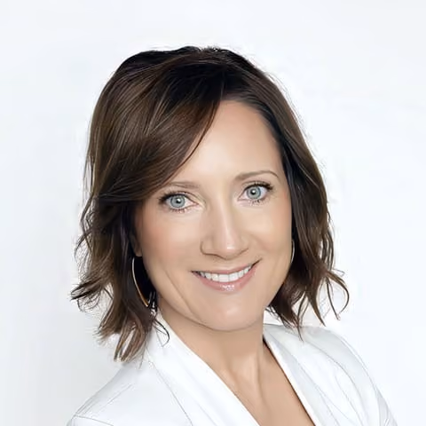 Woman with short wavy brown hair wearing hoop earrings and a white jacket smiling at the camera.