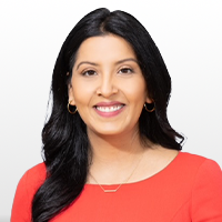 Headshot of a smiling woman with long black hair wearing a red top and gold hoop earrings.