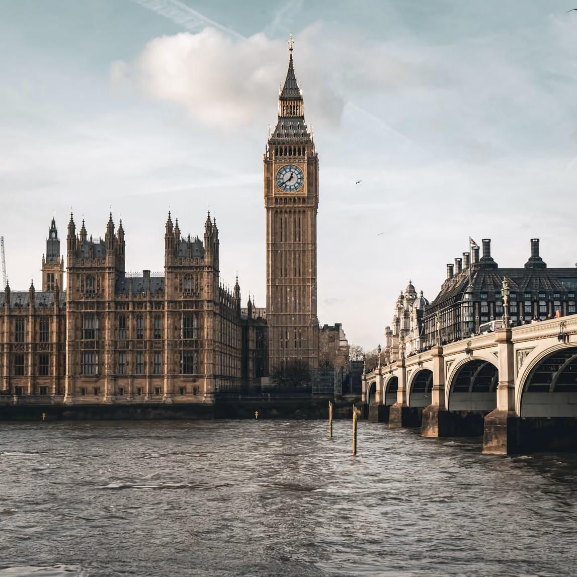 View of Big Ben clock tower, Palace of Westminster, and Westminster Bridge over the River Thames in London.