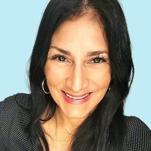 Smiling woman with long dark hair against a light blue background, wearing hoop earrings and a black top.