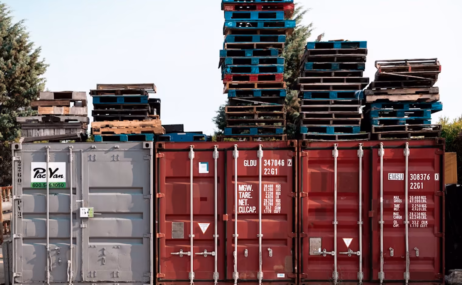Seecontainer mit darauf gestapelten bunten Paletten