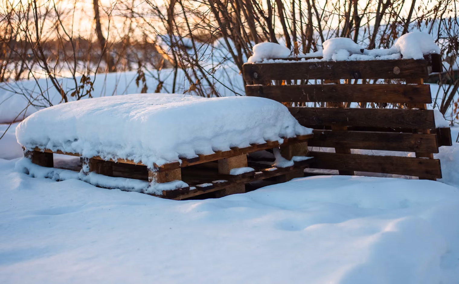 Schneebedeckte Holzpaletten auf einem Außengelände im Winter