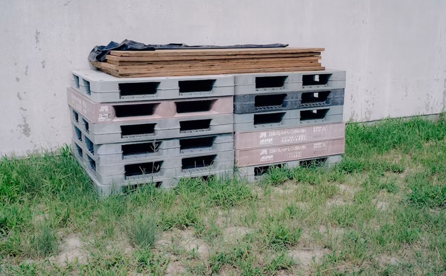 Gestapelte Paletten im Freien an einer Hallenwand