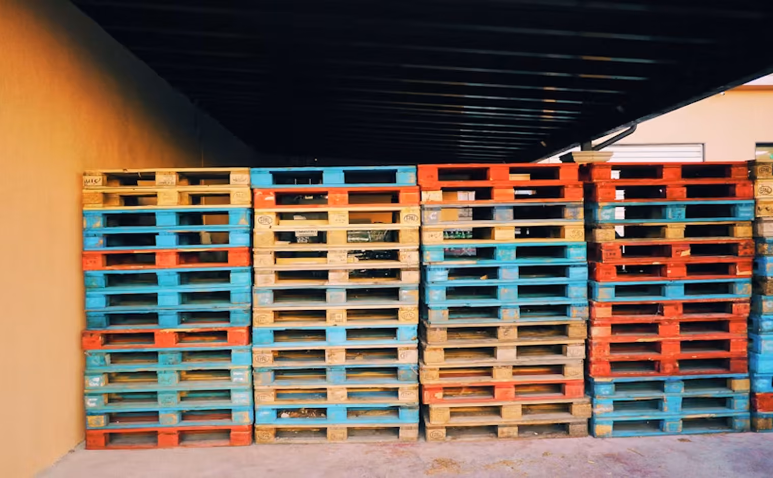 Stapel bunter Kunststoffpaletten in einer Lagerhalle