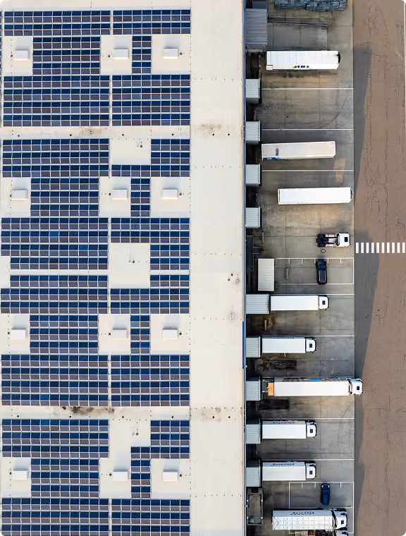 Aerial view of a distribution centre with a solar roof and trailers at the loading doors