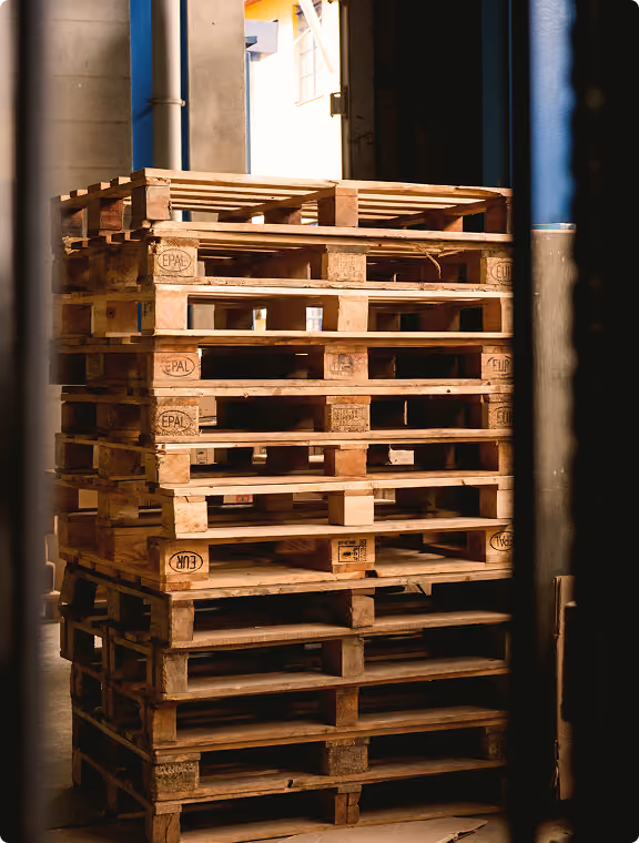 Stacked empty Euro pallets at a warehouse gate