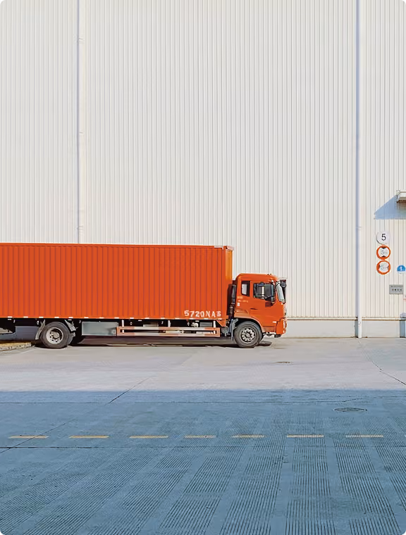 Truck with a red swap body in front of a warehouse facade