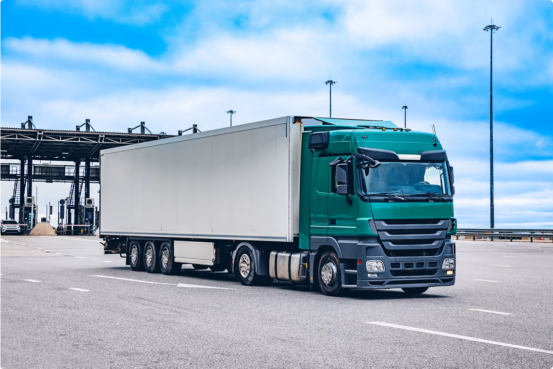 Truck with a green tractor unit and white trailer on the road