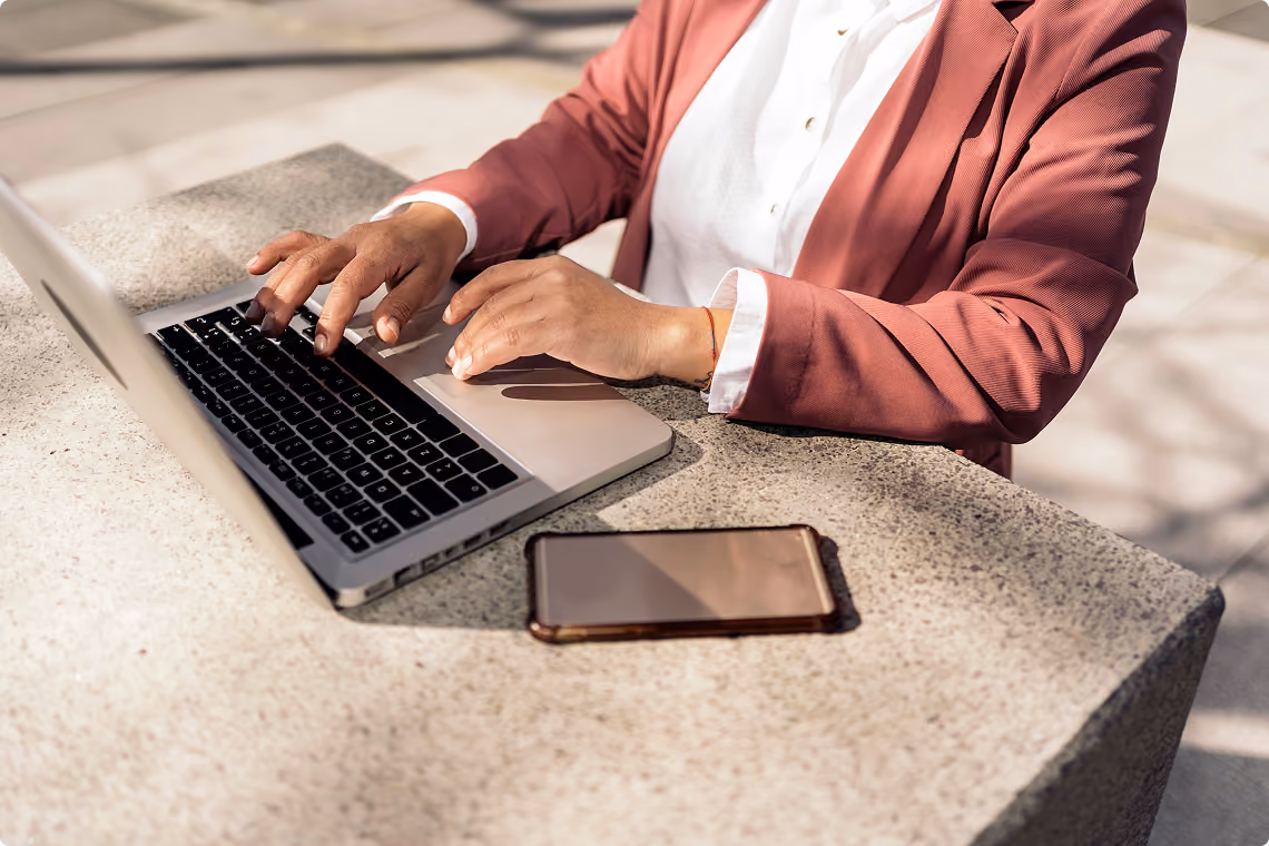 Person working on a laptop with a smartphone on the desk