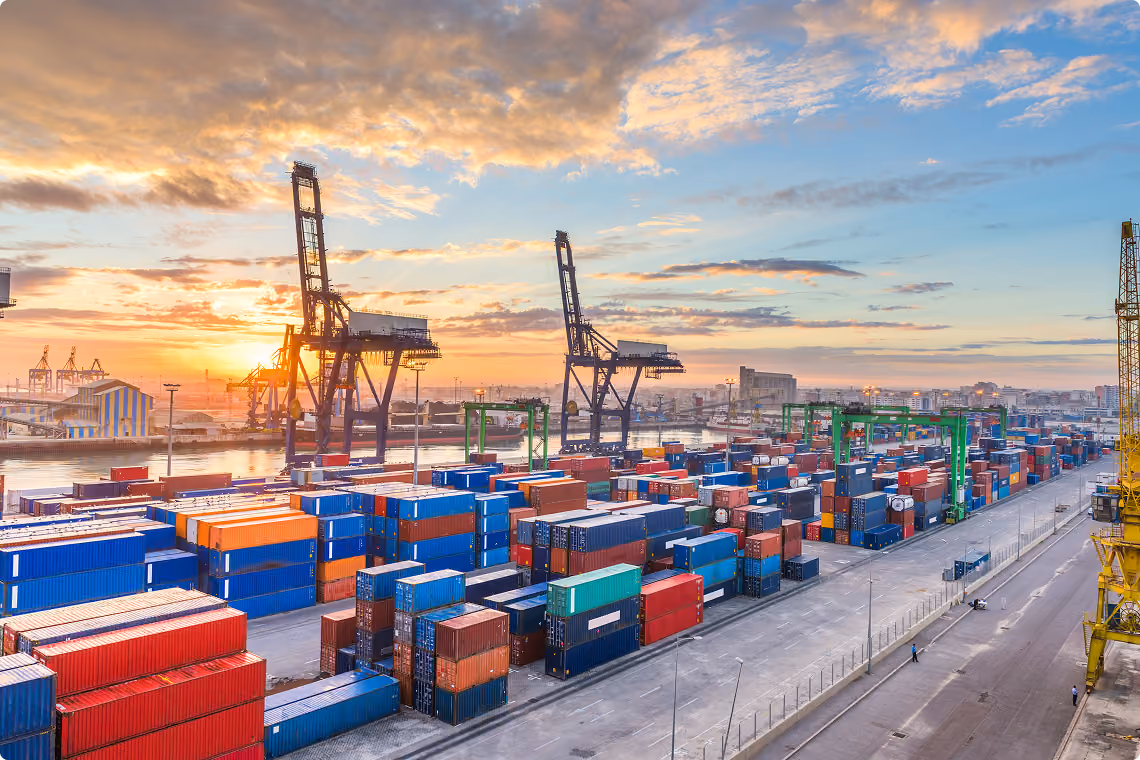 Container terminal with gantry cranes and stacked containers at dusk