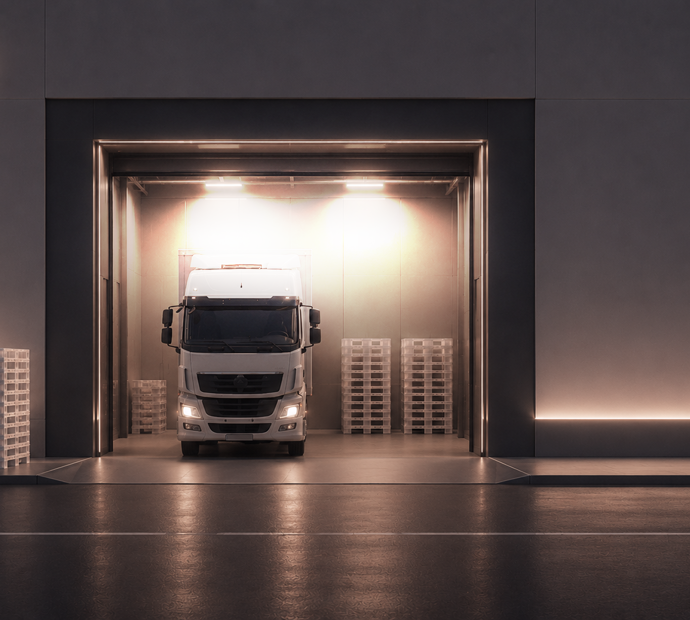 Lkw in einem beleuchteten Hallentor neben Palettenstapeln
